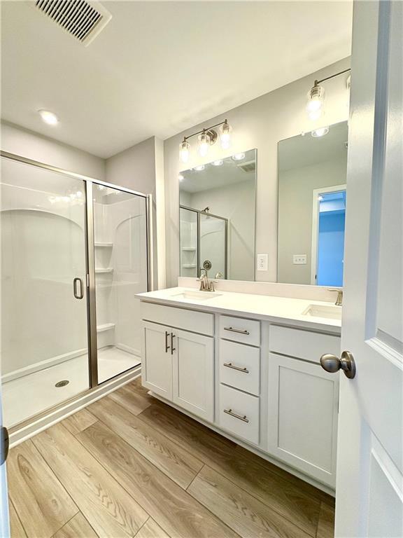 Modern master bathroom featuring double white vanity, frameless glass shower, and light wood flooring in Davidson Homes The Monroe A, Emerson, Georgia