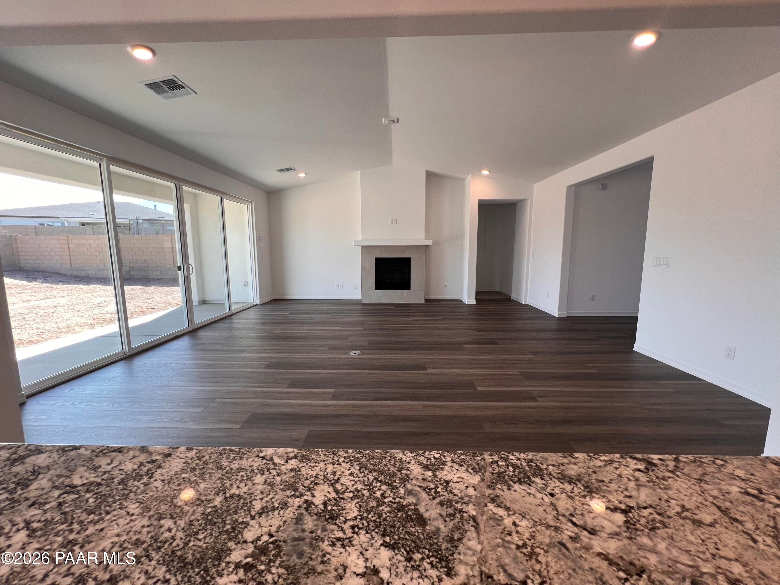 Spacious living room with gas fireplace, hardwood floors, and sliding doors to backyard in Davidson Homes The Summit A, Prescott, Arizona