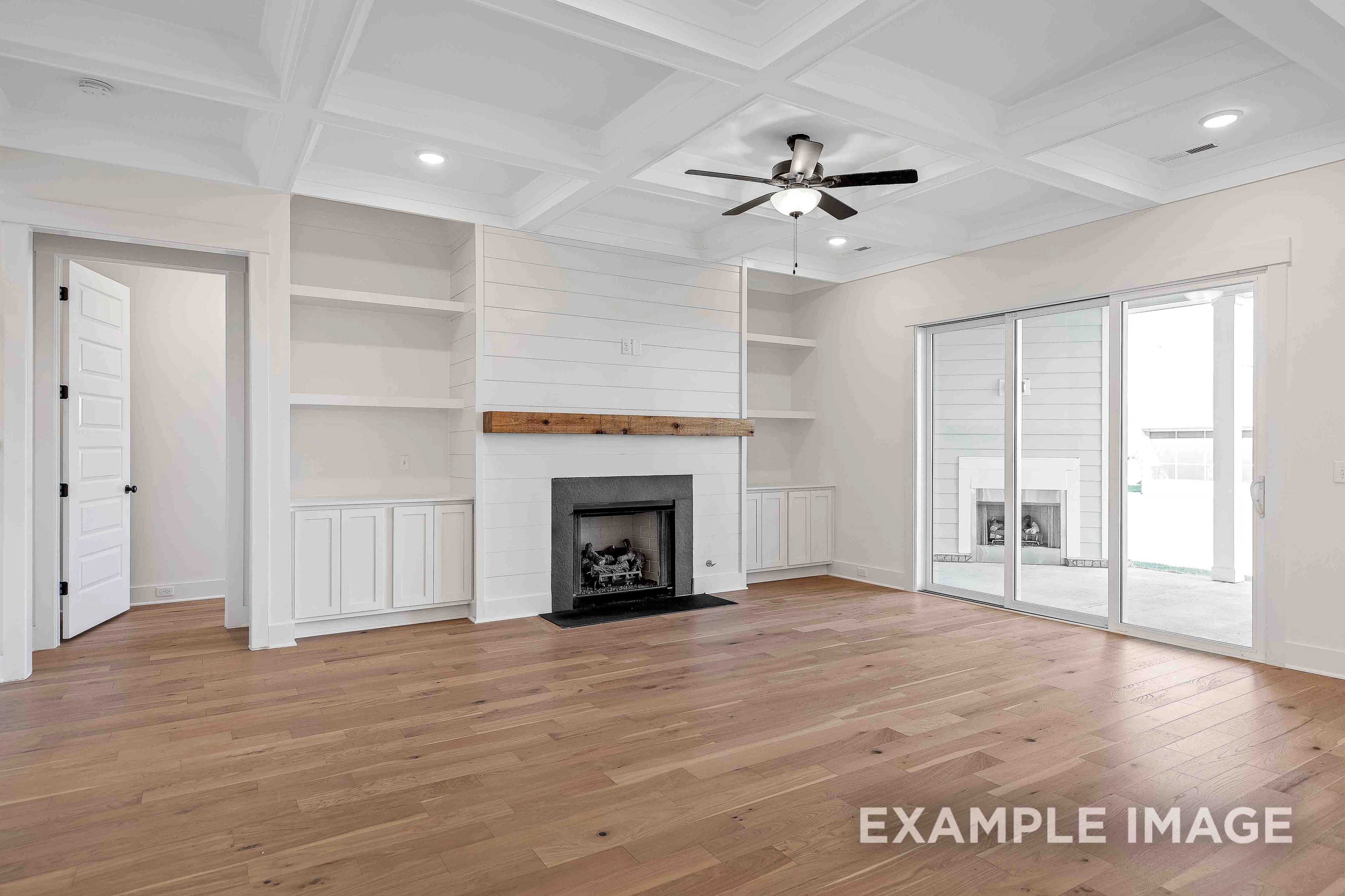 Spacious great room in The Albany A with shiplap walls, built-in shelves, stone fireplace, and sliding doors to patio