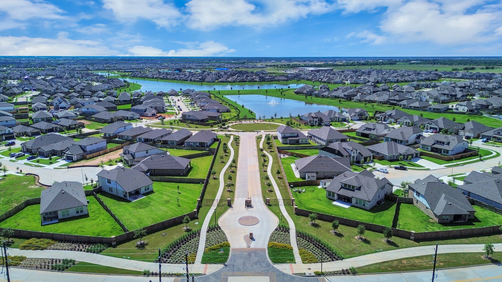 Open-concept living room in Sunterra Katy Texas by Davidson Homes with gas fireplace TV dining area and modern seating