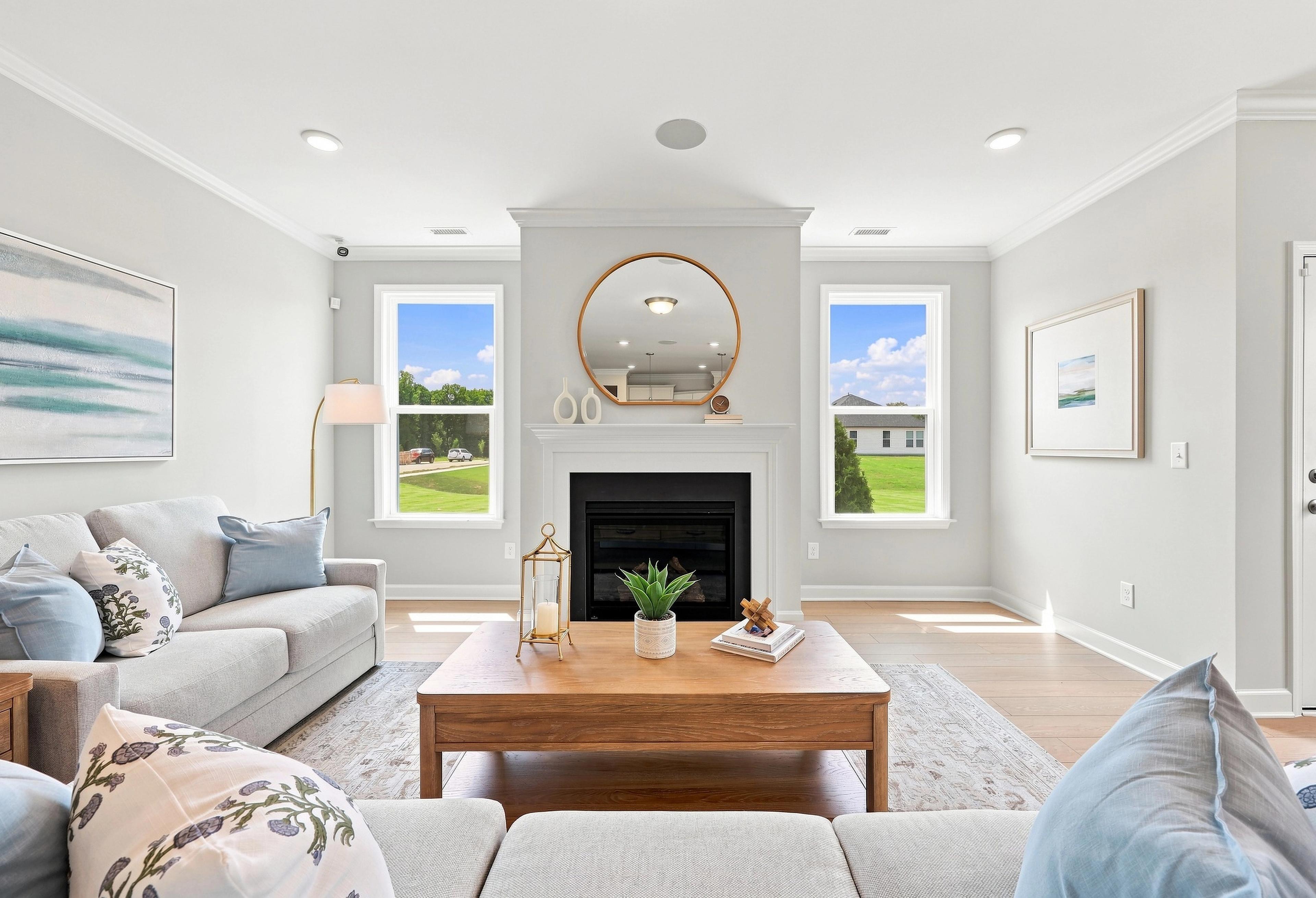 Bright living room in The Daphne C featuring a cozy fireplace, wood coffee table, and large windows with natural light.