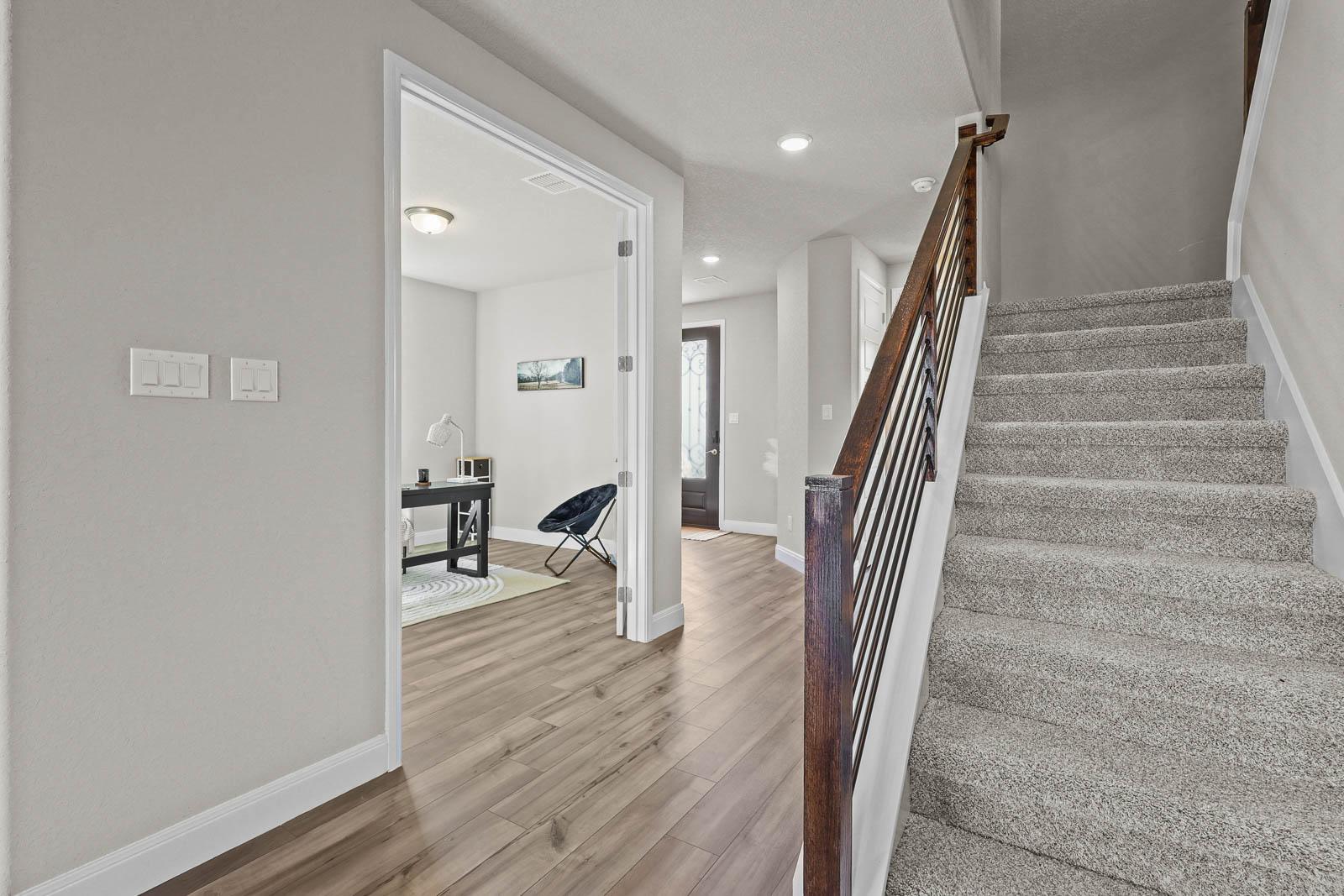 Foyer and staircase in The Jennings G featuring wood-look flooring, carpeted stairs, and a French-door home office.