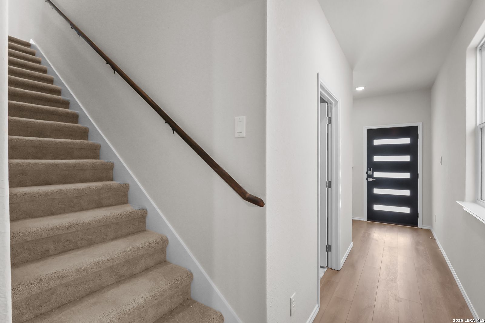 Entryway with carpeted stairs and modern black front door in The San Marcos F floor plan by Davidson Homes, San Antonio.