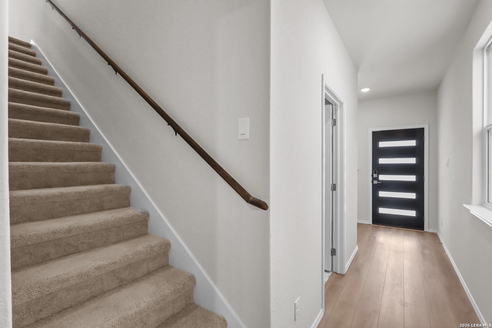 Entryway with carpeted stairs and modern black front door in The San Marcos F floor plan by Davidson Homes, San Antonio.