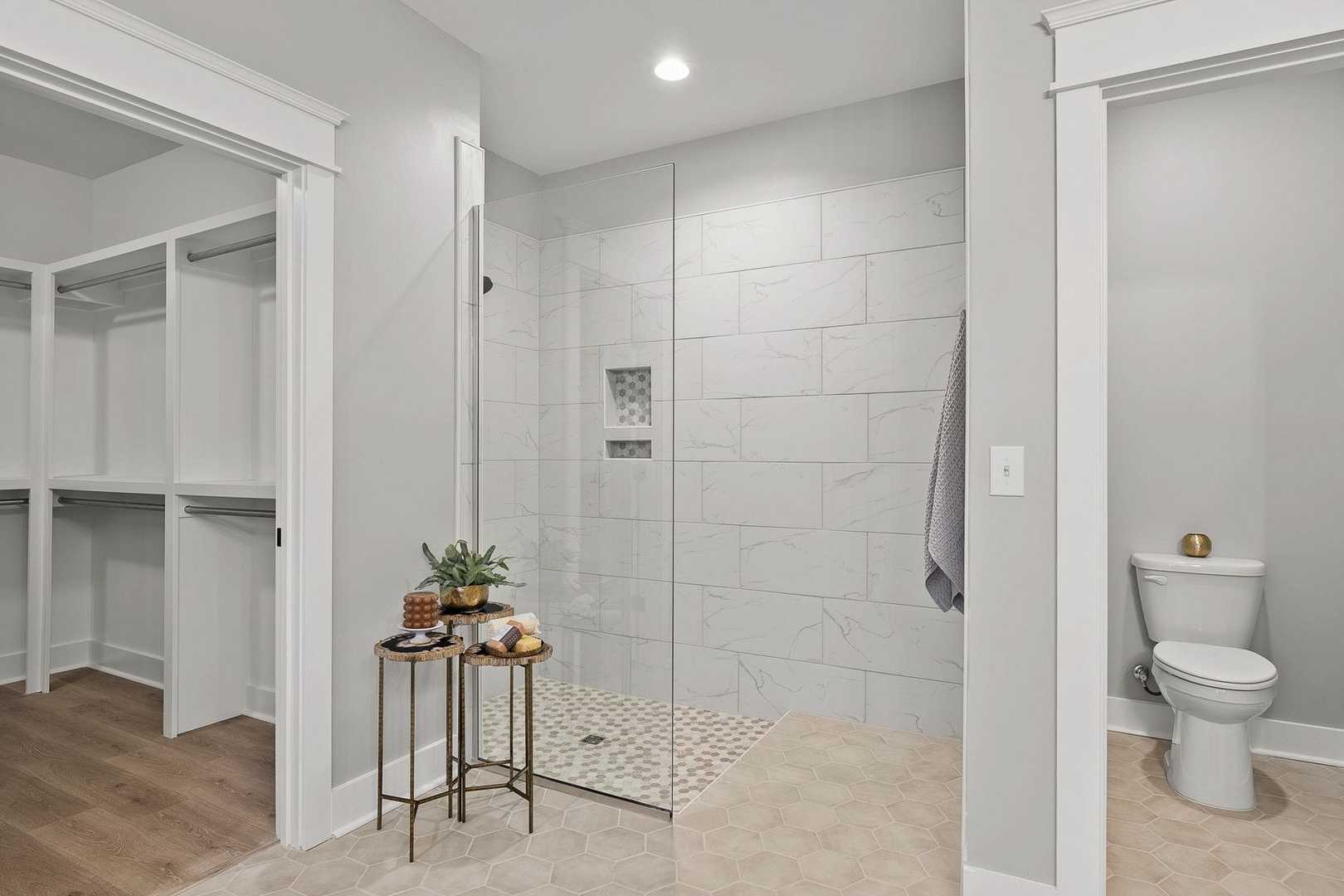 Spacious The Oxford master bathroom with walk-in closet, frameless glass shower, subway tile walls, and adjacent water closet