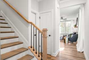 Spacious oak staircase with black balusters in The Washington H townhome, open to airy living area, Davidson Homes Marietta GA