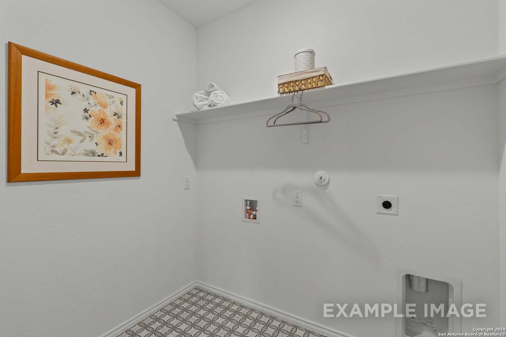 Bright laundry room with utility sink, built-in shelves, floral wall art in The Daphne K floor plan, Royal Crest, San Antonio