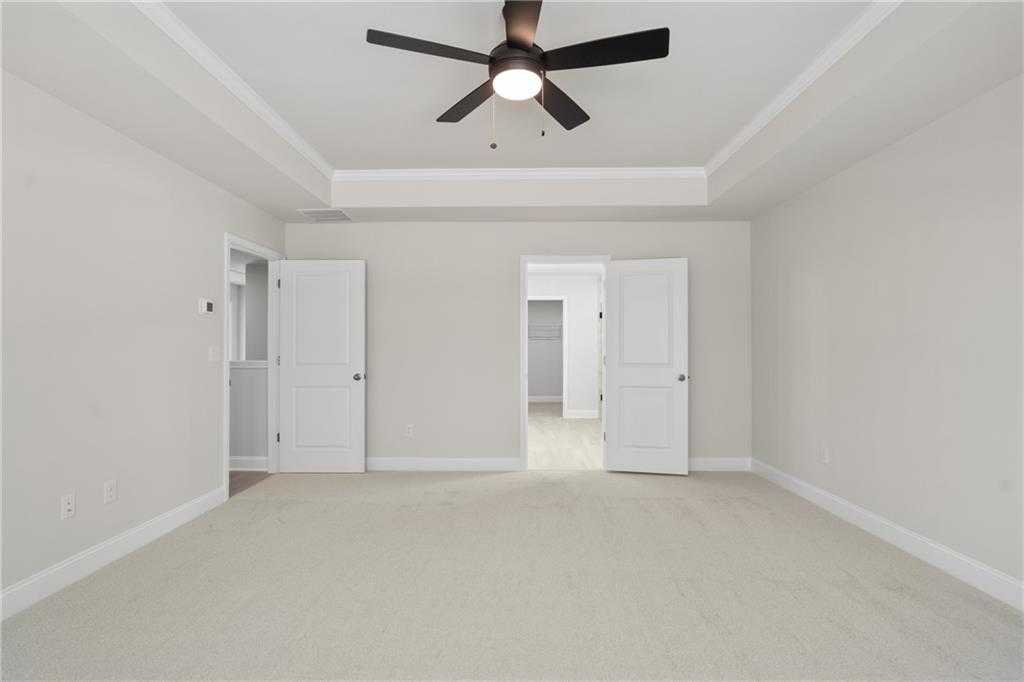 Spacious master bedroom with ceiling fan, tray ceiling, and en suite doors in Davidson Homes The Hickory B, Buford, GA