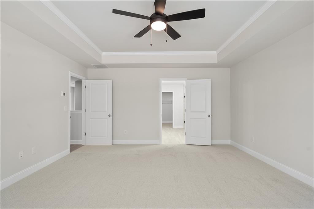 Spacious master bedroom with ceiling fan, tray ceiling, open closet and bathroom doors in Davidson Homes The Hickory E, Buford, GA