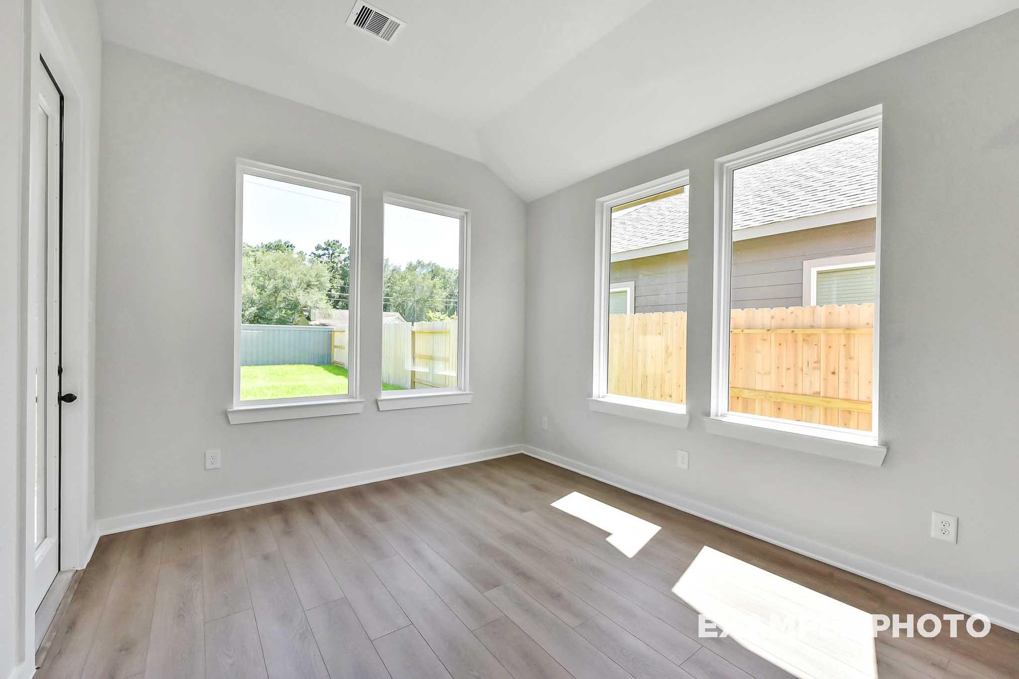 Bright master bedroom in The Sequoia home with vaulted ceiling, large windows, hardwood floors, and backyard view