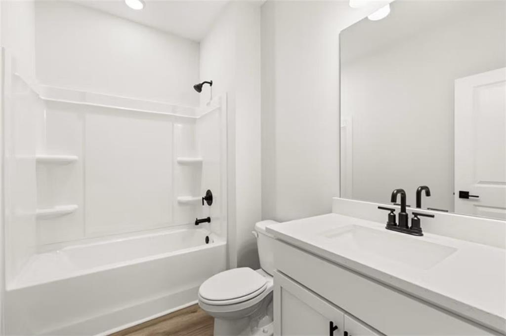 Bright white secondary bathroom with tub, walk-in shower, single vanity, and black fixtures in Davidson Homes The Hickory B, Winder, Georgia