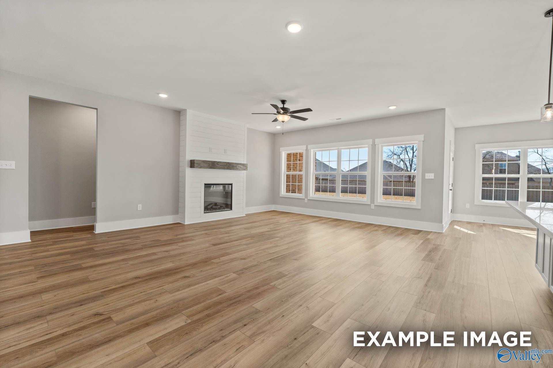 Spacious open-concept living room with fireplace and wood-look flooring in The Finleigh by Davidson Homes, Meridianville.