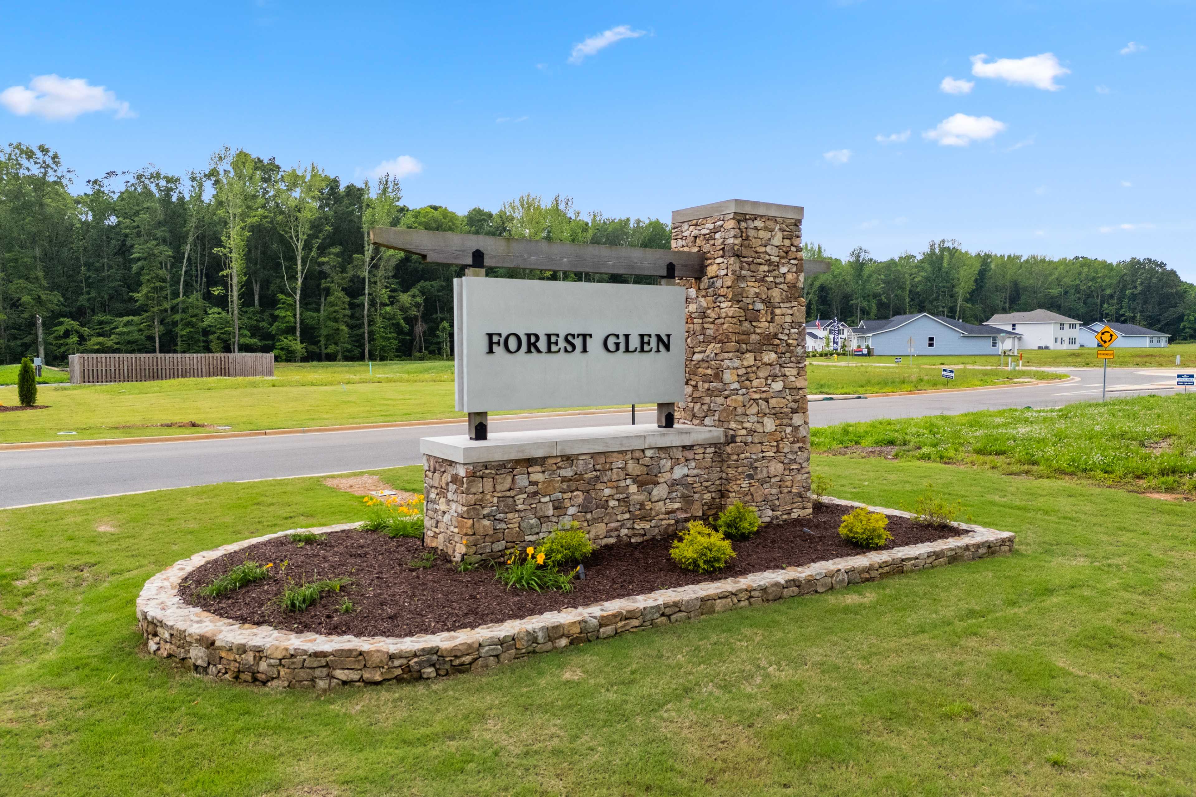 Forest Glen entrance sign in Hazel Green Alabama with stone pillars, lush greenery, and new homes backdrop