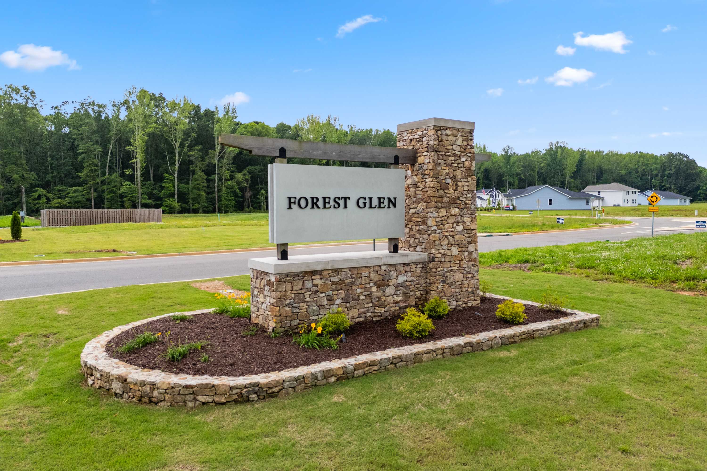 Forest Glen entrance sign in Hazel Green Alabama with stone pillars, lush greenery, and new homes backdrop