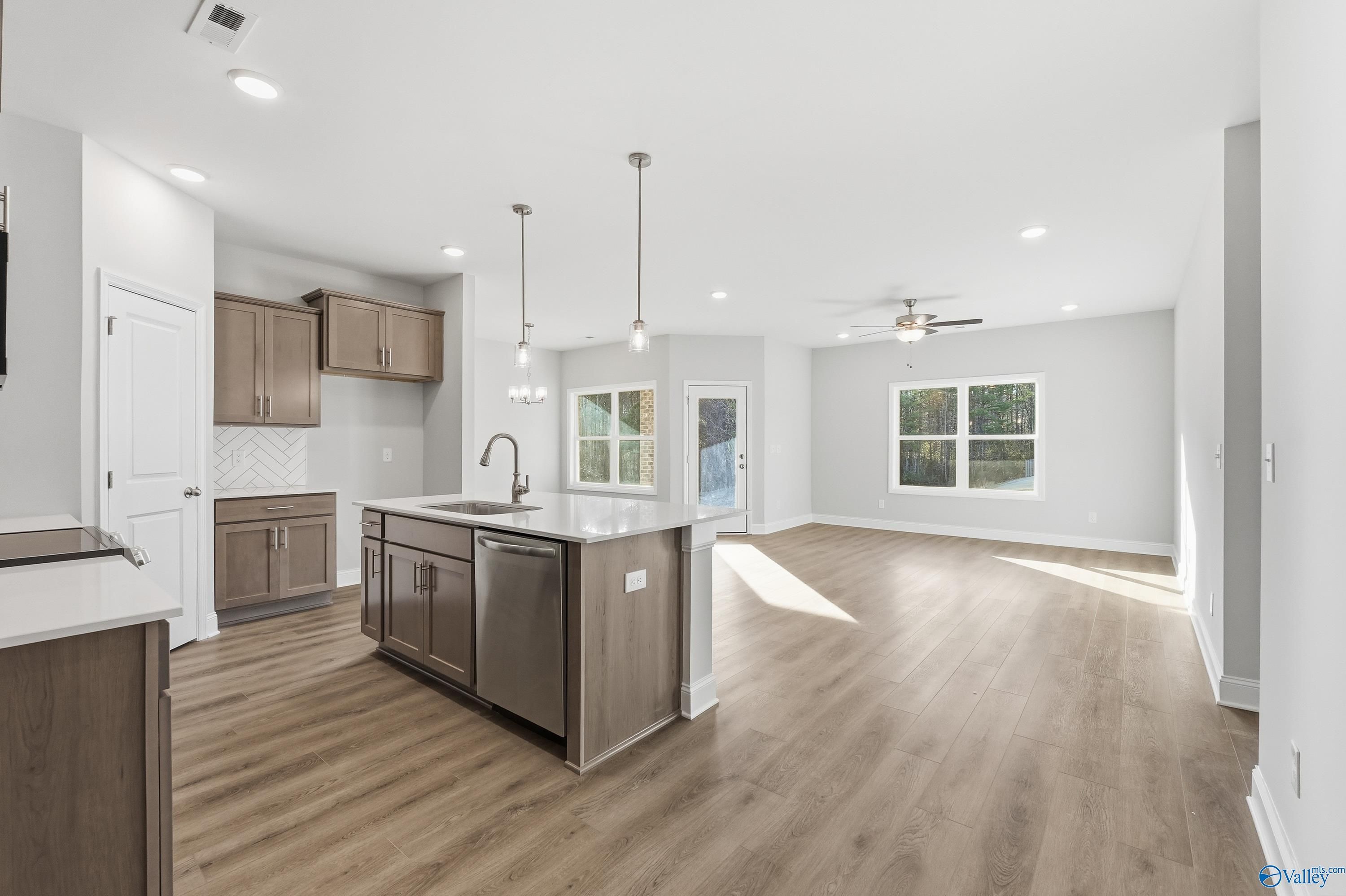 Open-concept kitchen with large wood island, stainless sink, shaker cabinets, and ample natural light in The Daphne C, Arab, AL