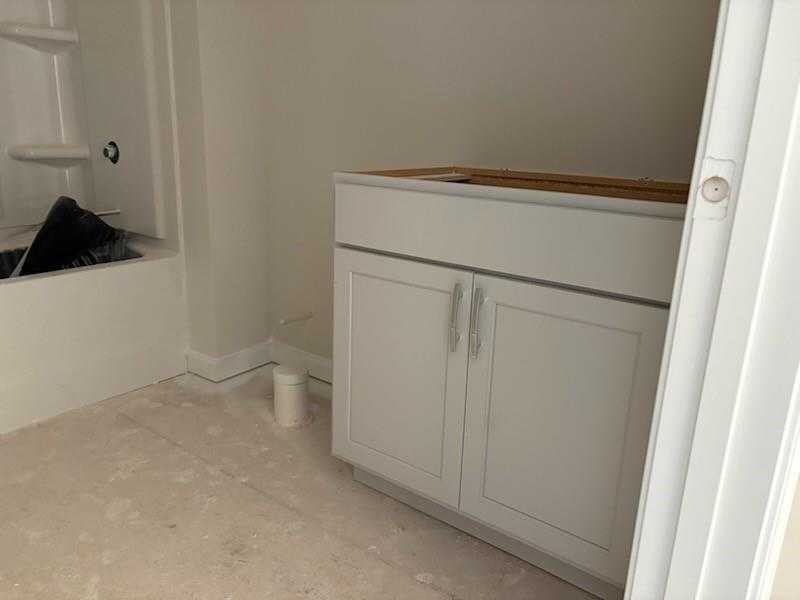Unfinished bathroom with white bathtub and partially assembled white vanity in Davidson Homes The Hickory A, Riverwood, Dallas, Georgia
