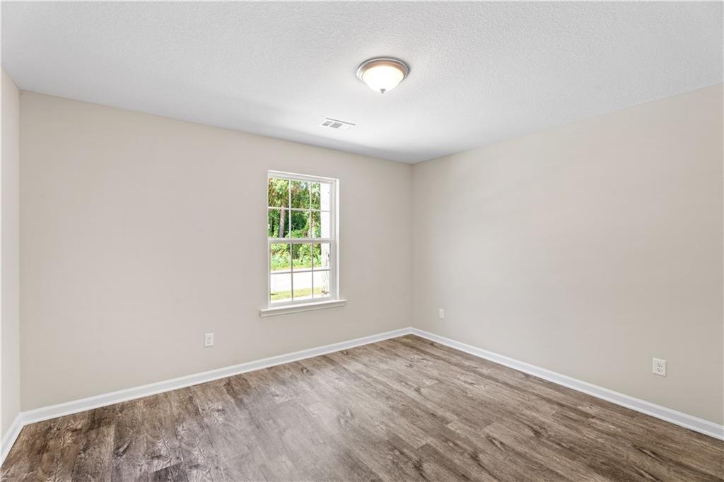 Bright secondary bedroom with neutral walls, large window, and warm hardwood floors in Davidson Homes The Washington, Phenix City