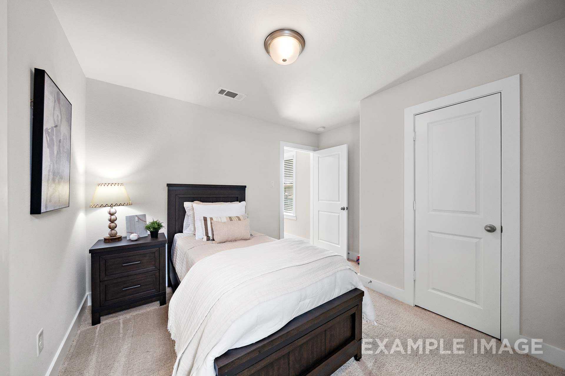 Cozy secondary bedroom in The Lily A Davidson Homes design with wooden bed, neutral gray walls, abstract art
