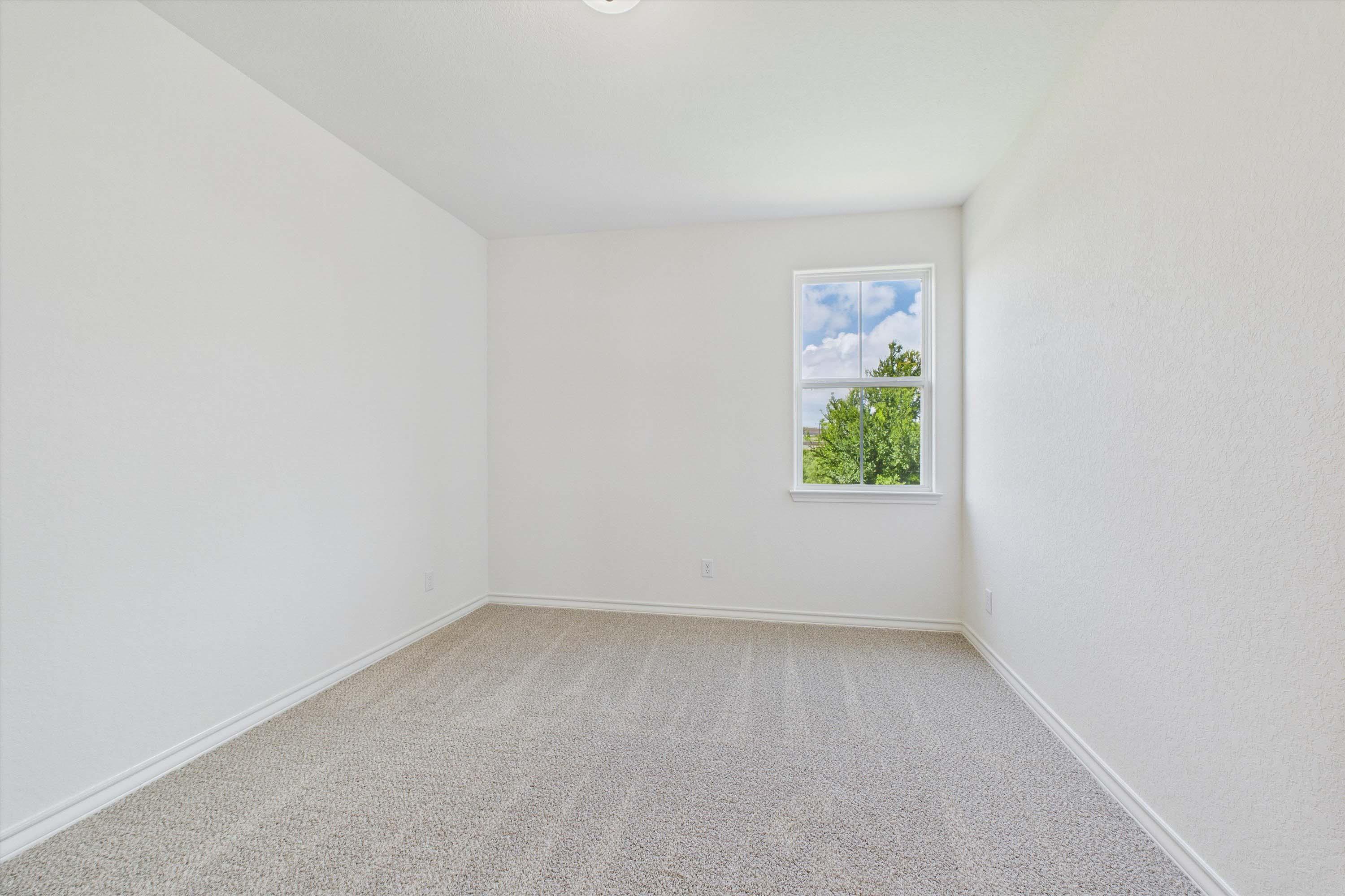 Bright, minimalist secondary bedroom with neutral carpet and natural light in The Danbury home design by Davidson Homes.