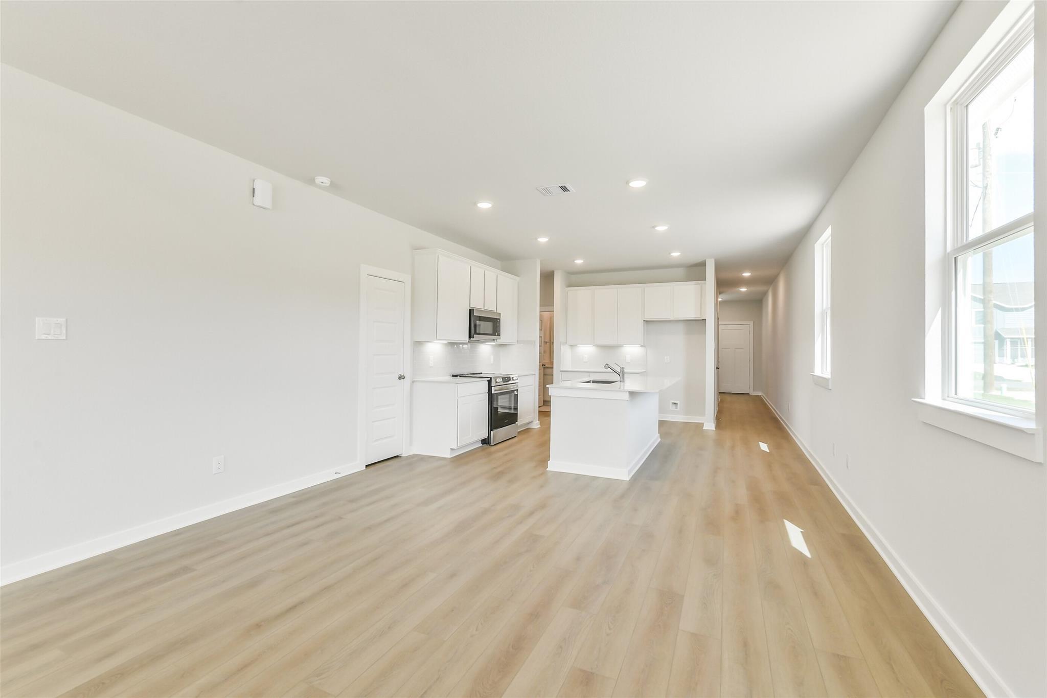 Open-concept kitchen with white shaker cabinets, large island sink, stainless appliances in Davidson Homes The Frio G, Conroe, Texas