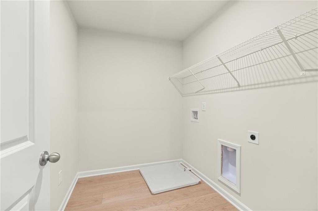 Bright laundry room with wire shelving, washer/dryer hookups, and pet door in Davidson Homes The Cary A, Kennesaw, Georgia