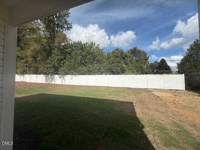 Spacious backyard with white privacy fence, mature trees, and green lawn in Davidson Homes The Preston C, Gregory Village, Lillington, NC