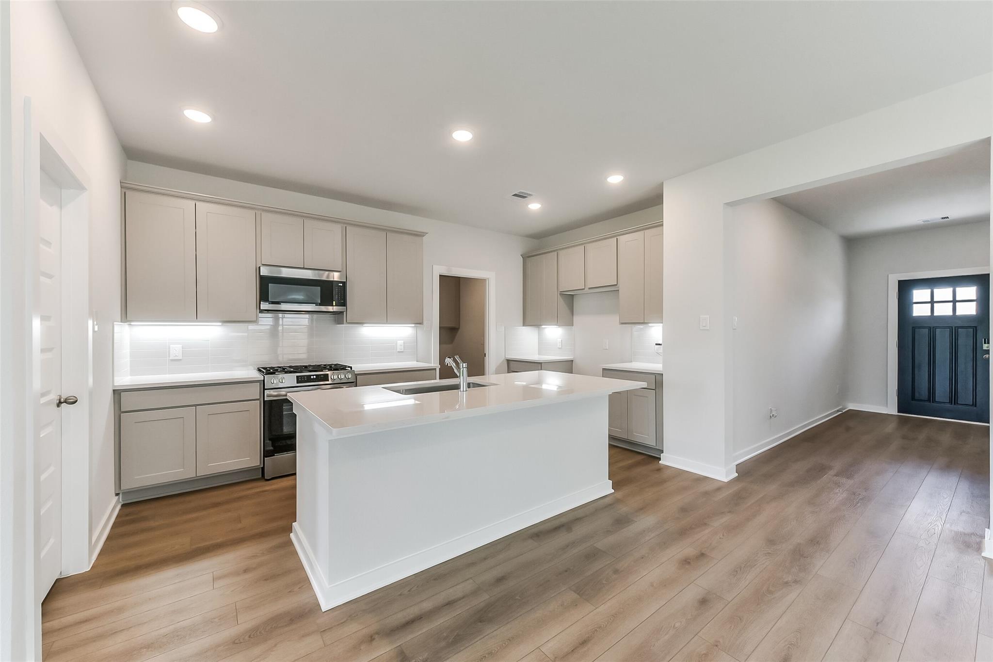 Modern kitchen with gray cabinets, white quartz island, stainless appliances in Davidson Homes The Tierra C, Dayton Texas