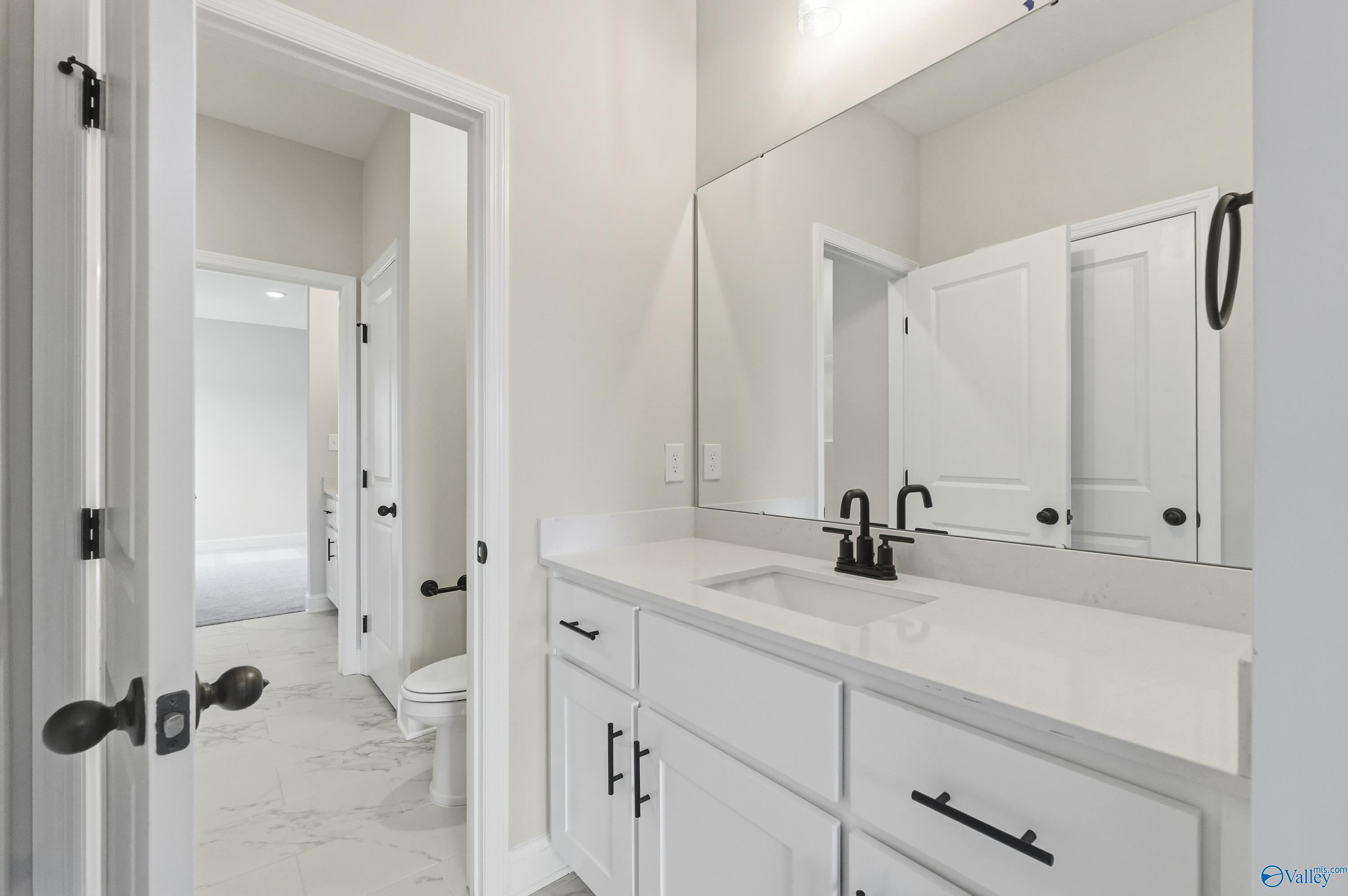 Modern powder room with white shaker vanity, quartz countertop, black faucet, and subway tile in Davidson Homes The Finleigh, Meridianville, Alabama