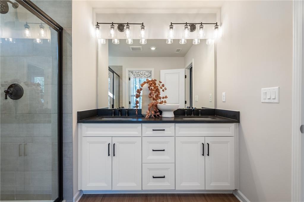 Modern master bathroom featuring double vanity, frameless glass shower, and lighted mirror in Davidson Homes The Marion B, Kennesaw, GA