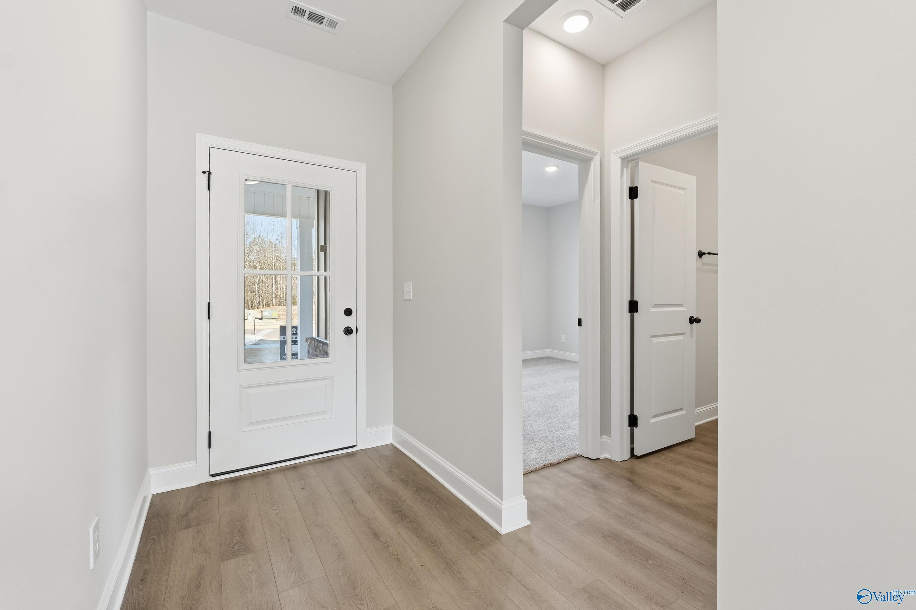 Bright entryway with glass-paneled front door and open doorway to carpeted room in 3-bedroom The Franklin E home, Hazel Green, AL