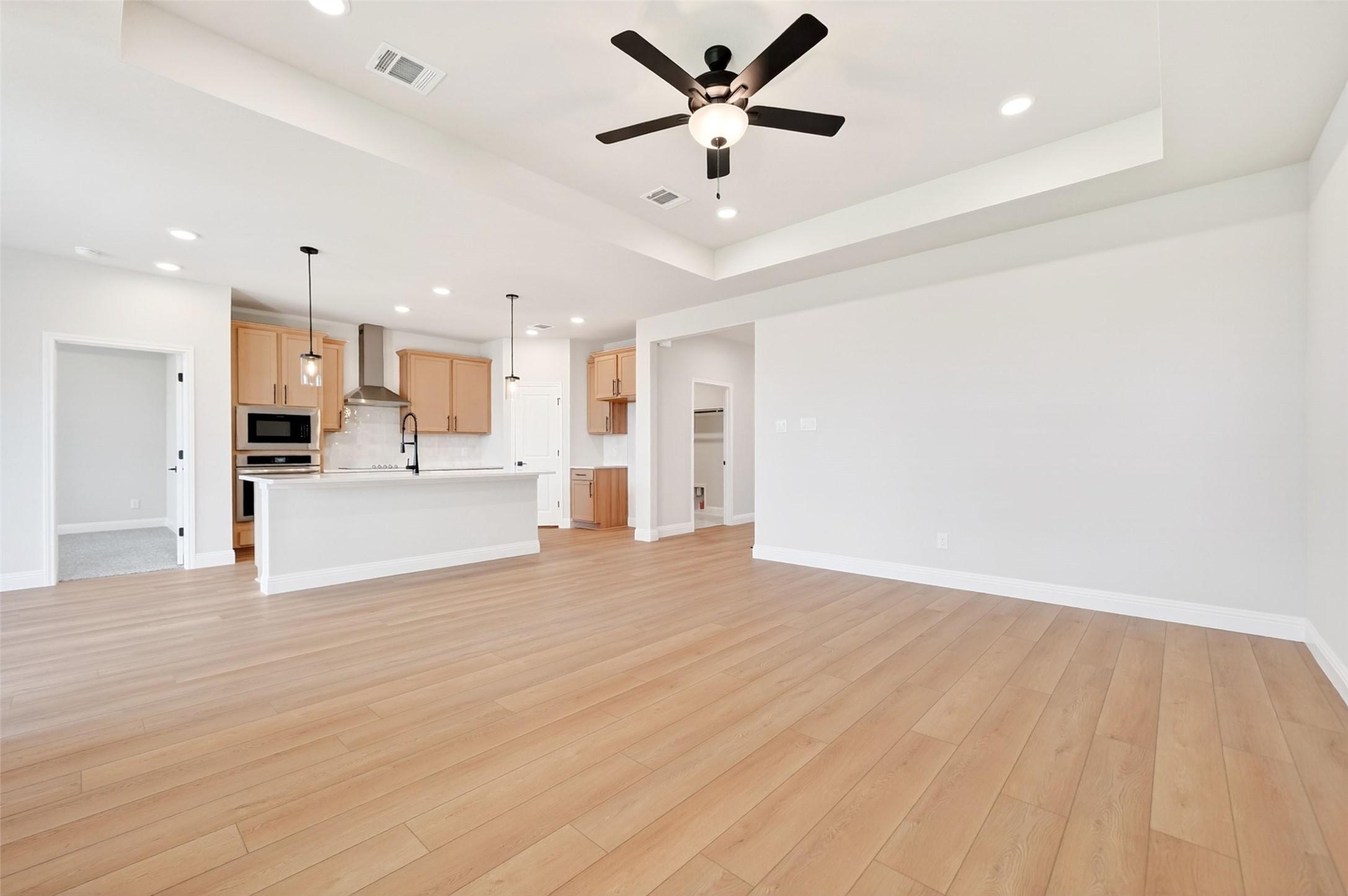 Open-concept living room and kitchen with wood flooring in The Holly C floor plan by Davidson Homes in Anna, Texas.