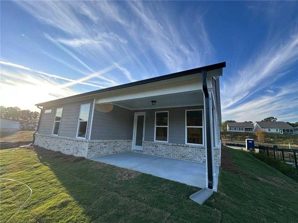 Gray brick single-story home with covered patio, large windows, and lush green lawn in Kelly Preserve, Loganville, Georgia - Davidson Homes Glenwood C
