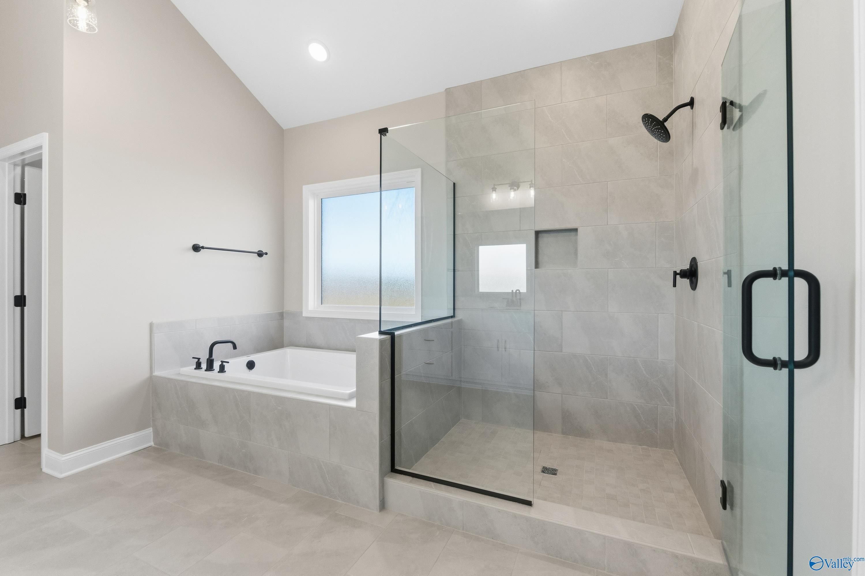 Modern master bathroom with freestanding tub, glass shower, and beige tiles in Davidson Homes The Finleigh, Meridianville, Alabama