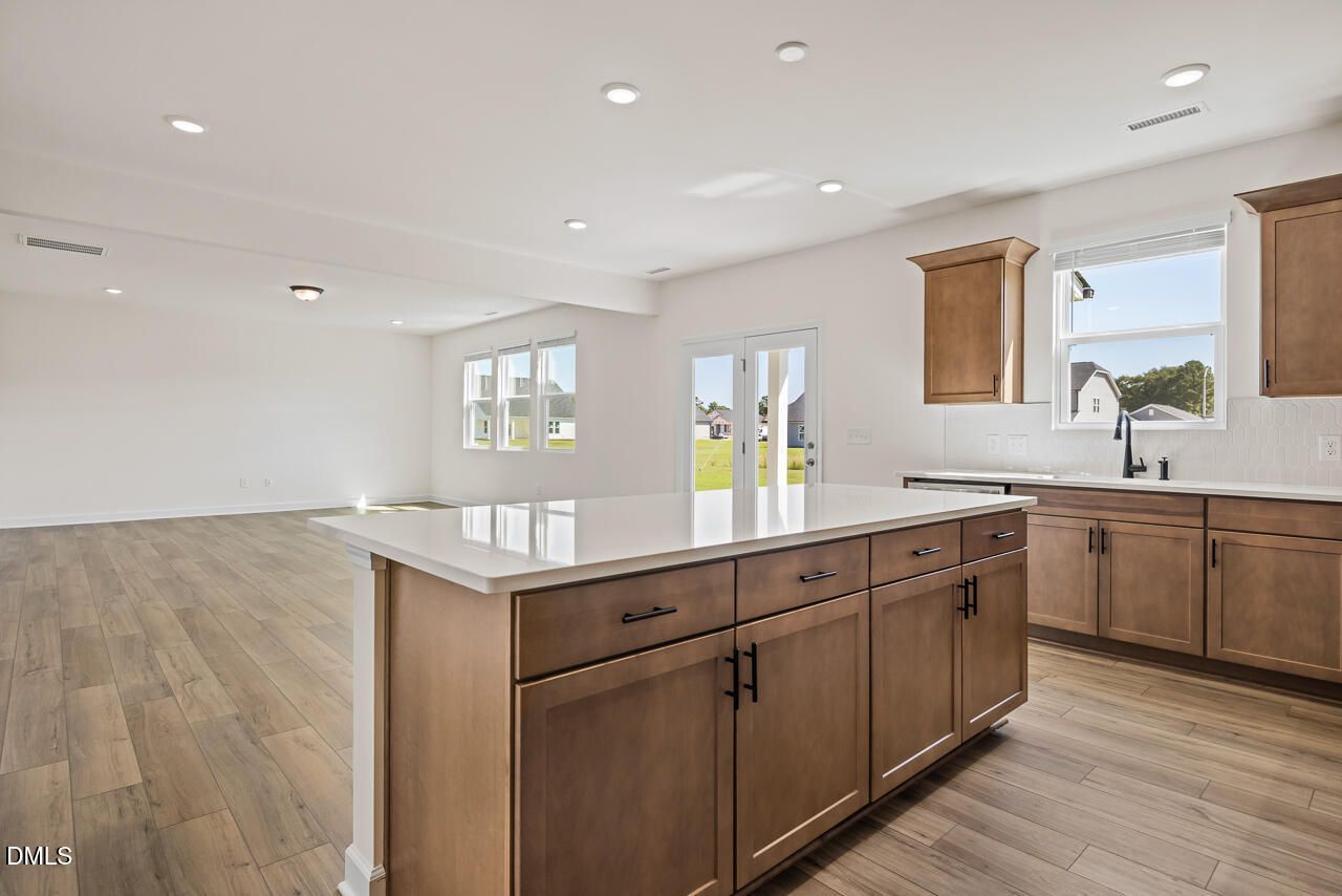 Open-concept kitchen with large island, wood cabinets, and luxury vinyl plank flooring in Davidson Homes' Hickory II B, Lillington, NC
