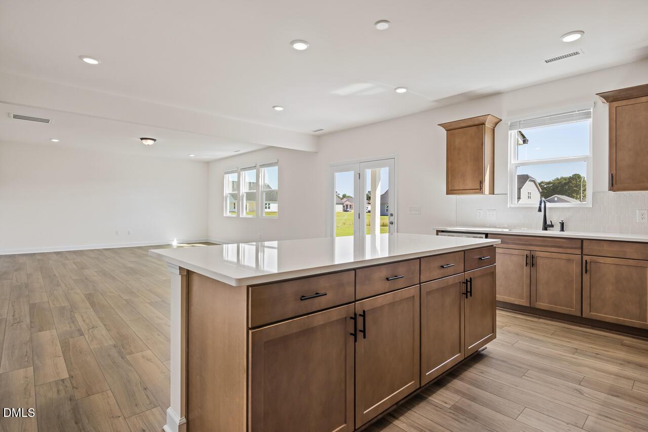 Open-concept kitchen with large island, wood cabinets, and luxury vinyl plank flooring in Davidson Homes' Hickory II B, Lillington, NC