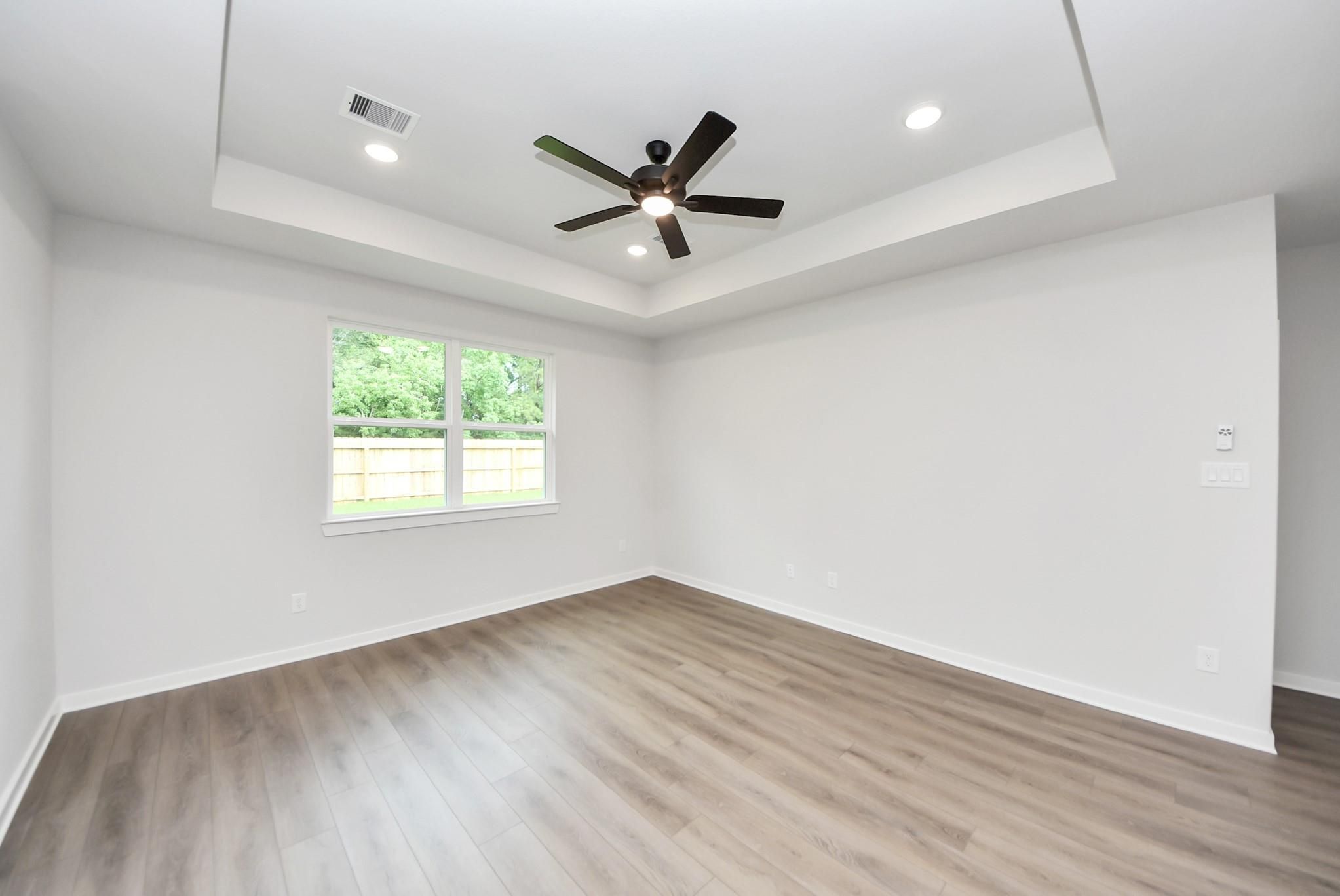 Bright bedroom with tray ceiling and ceiling fan in The Daphne F floor plan by Davidson Homes in Sundance Cove, Crosby.