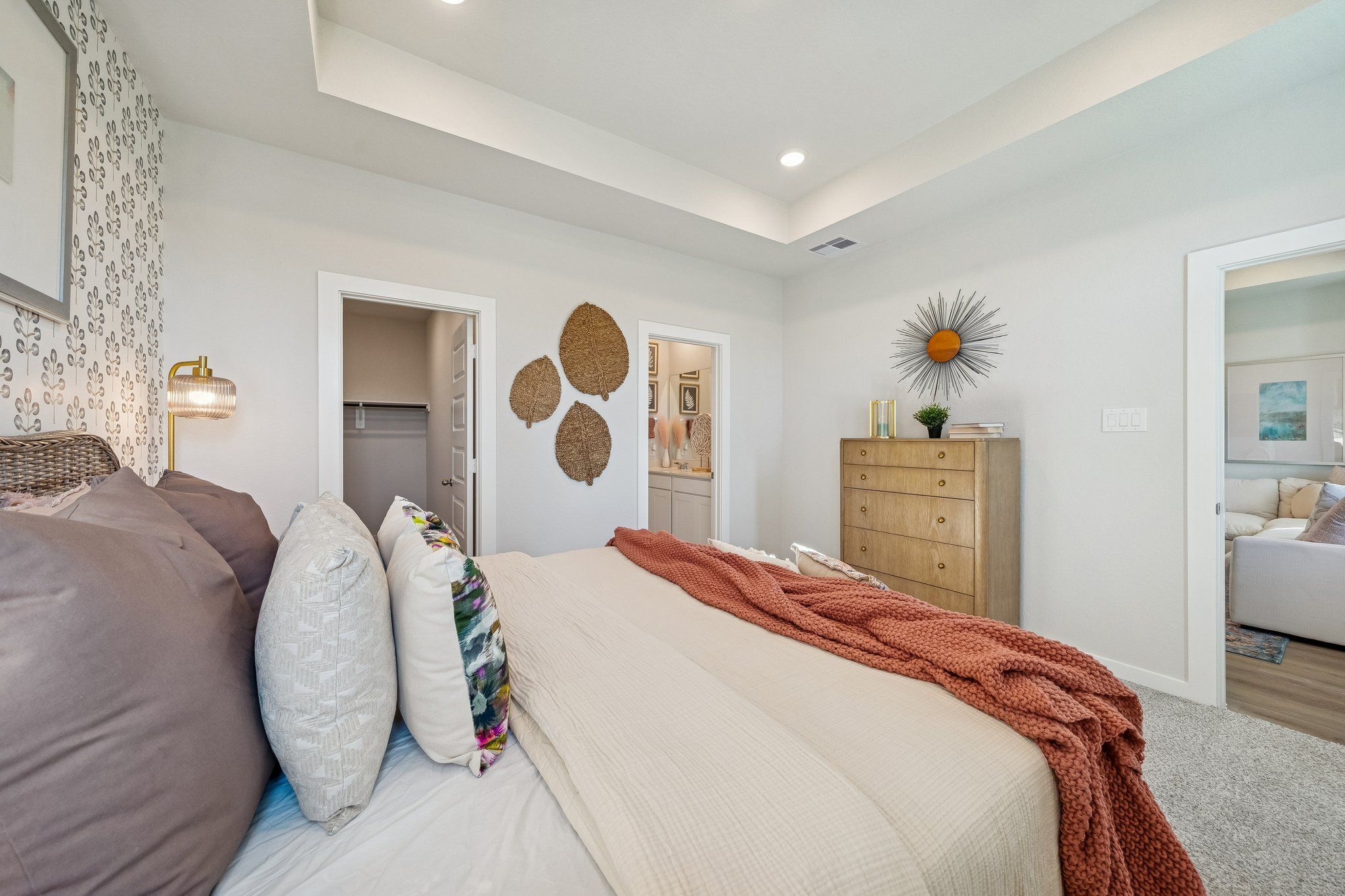 Spacious master bedroom at Spring Branch Crossing in Conroe Texas with king bed, woven wall art, sunburst decor and neutral palette