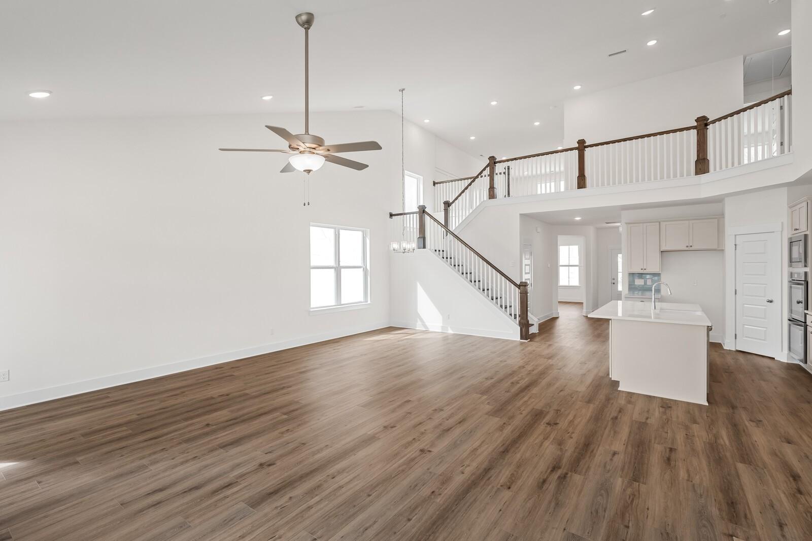 Expansive two-story foyer with oak staircase, ceiling fan, and open kitchen island in Davidson Homes The Ridgeport, Gallatin, TN