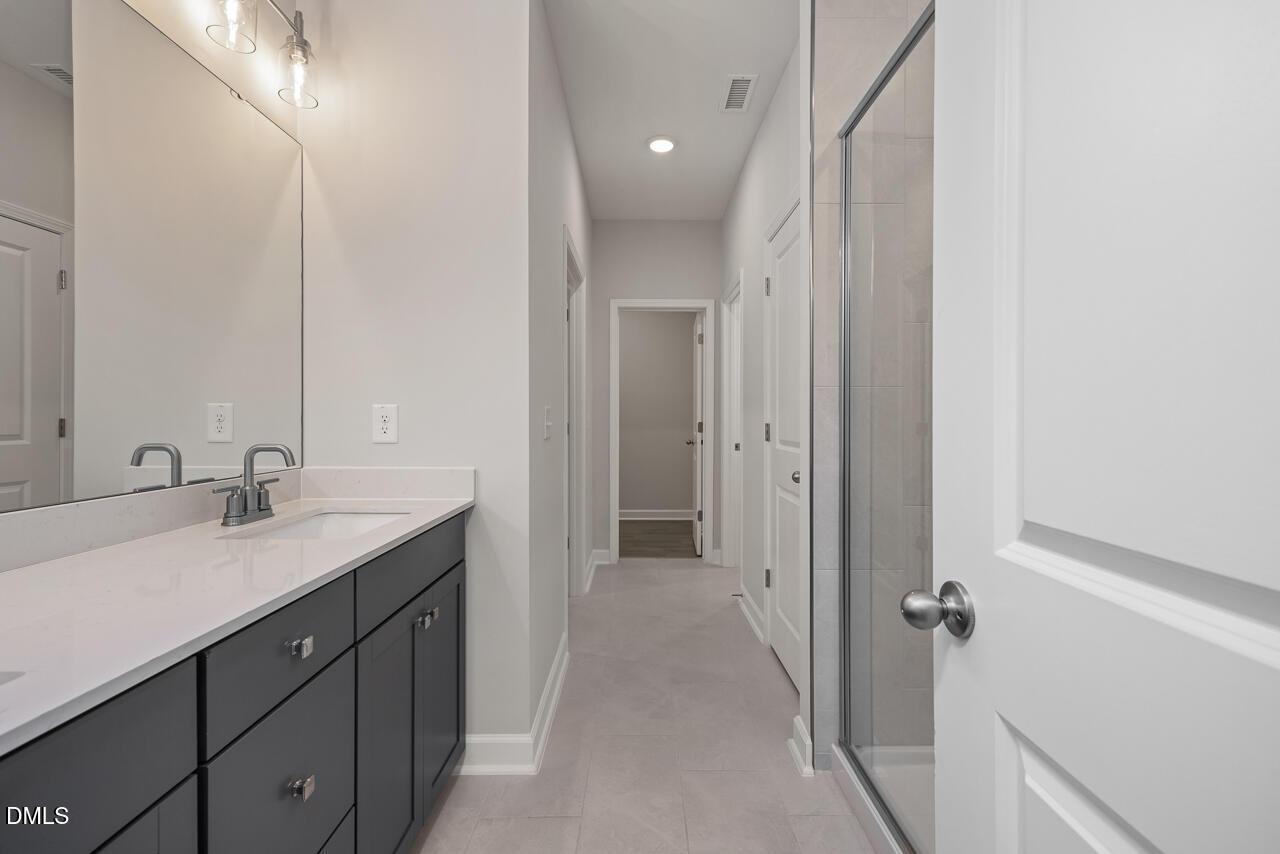 Modern primary bathroom with dark vanity and walk-in shower in The Ashport G floor plan, Sage on North Main, Wake Forest.