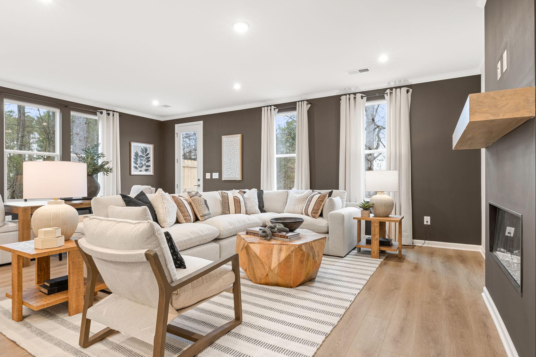 Spacious living room at Lake Shore in Winder GA with white sectional sofa, wood coffee table, fireplace, and large windows