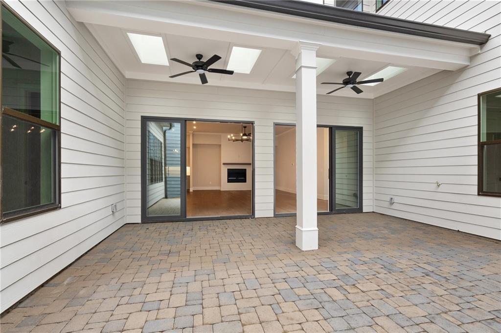 Covered patio with paver flooring, skylights, ceiling fans, and open glass doors to living area in Davidson Homes The Seaside B, Woodstock, GA