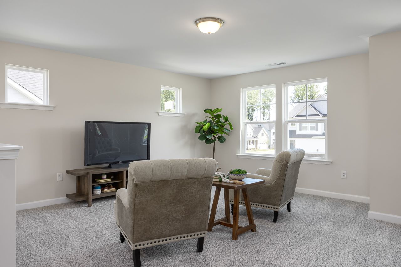 Spacious loft area in The Chestnut home design featuring cozy seating, media console, and natural light in Belmont, NC.
