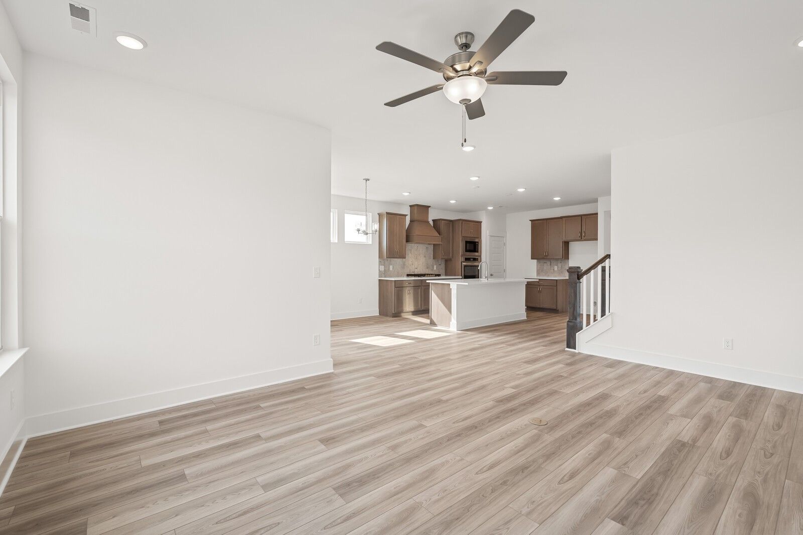 Open-concept living and kitchen with hardwood floors, white cabinets, island, and ceiling fan in Davidson Homes The Ash C, Mt. Juliet, TN