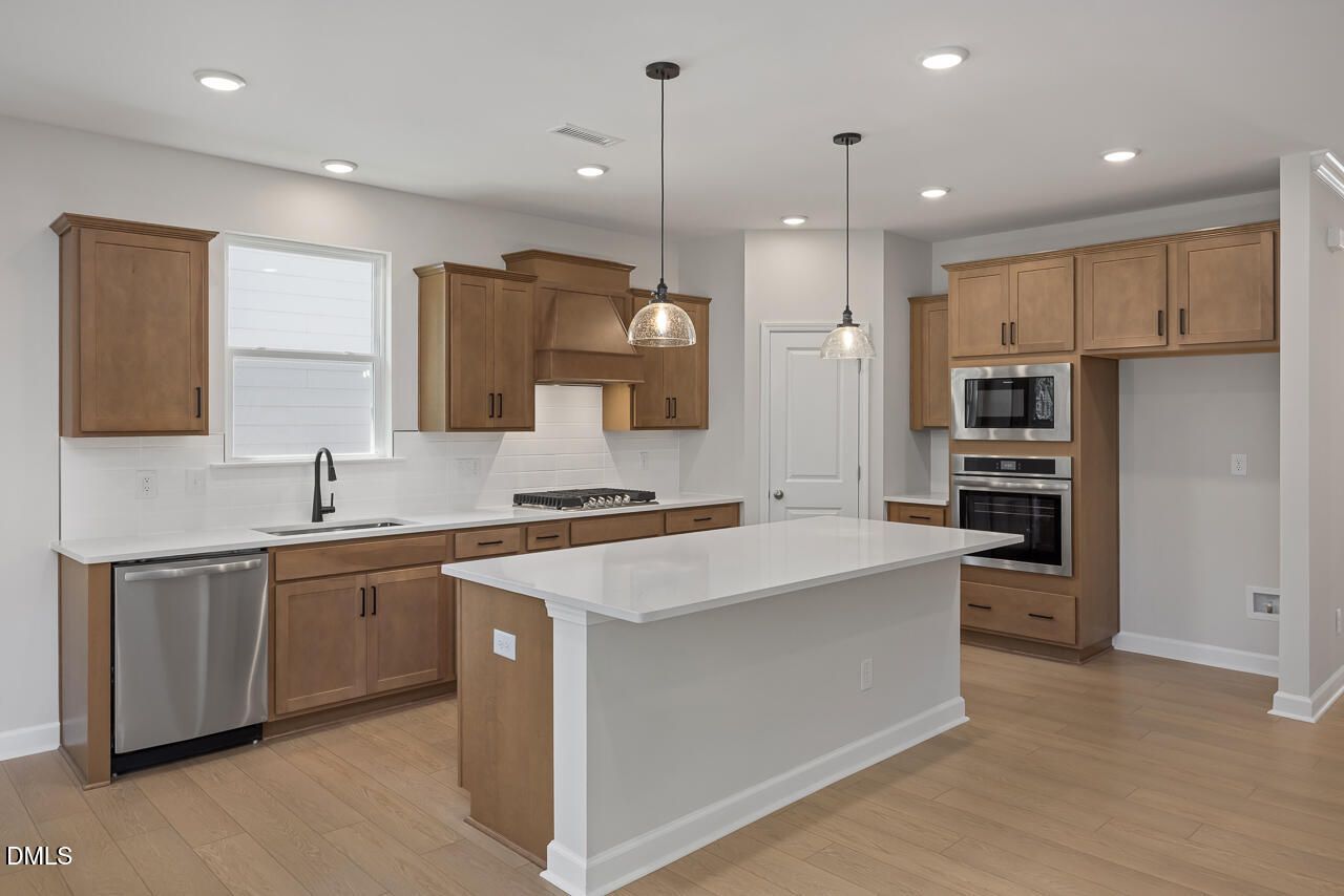 Modern kitchen with quartz island, wood cabinets, and stainless steel appliances in The Ashport L at Sage on North Main.