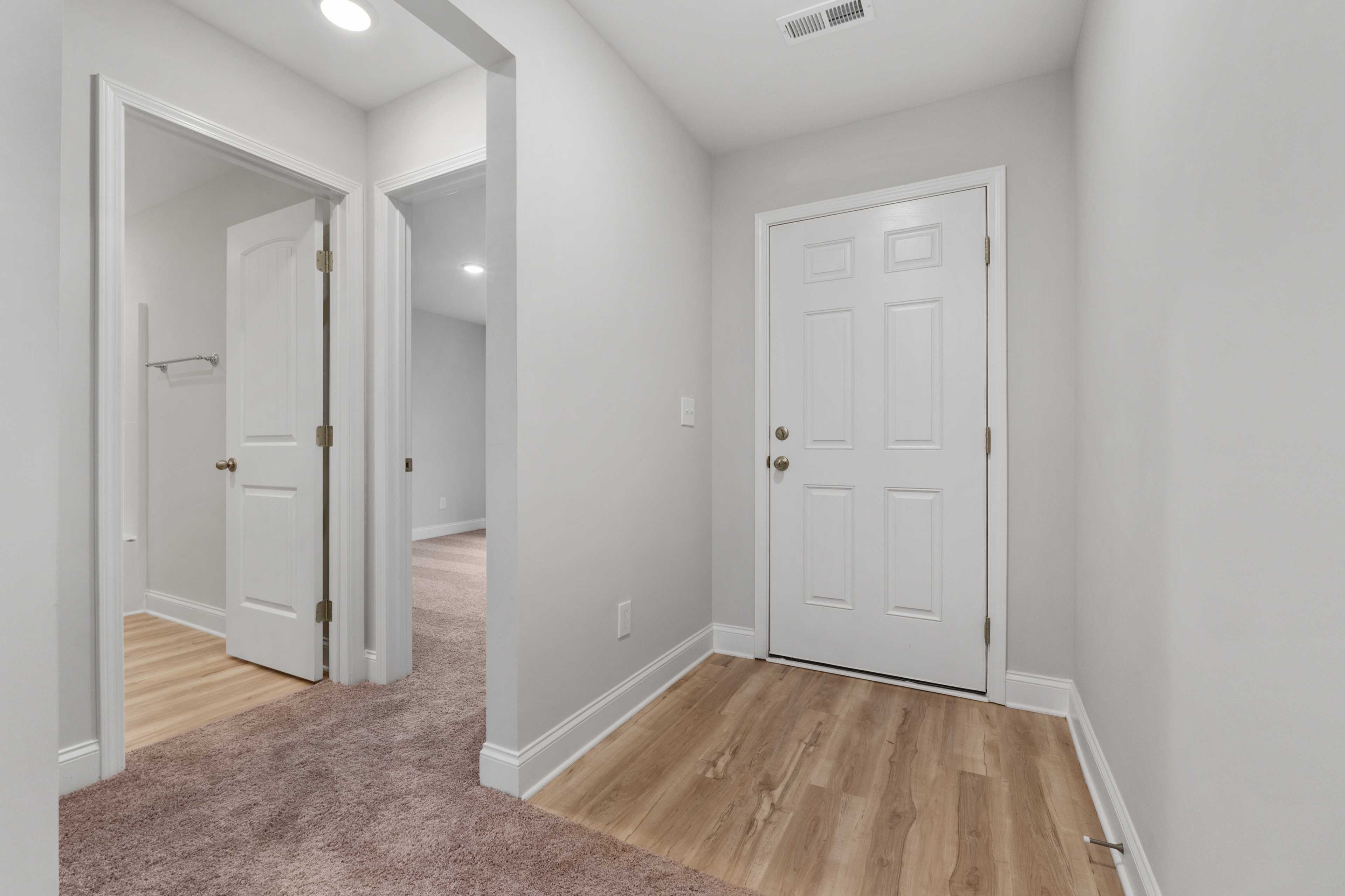 Bright hallway in Collins Lane home, Meridianville AL with white doors, light gray walls, carpet, and hardwood floors