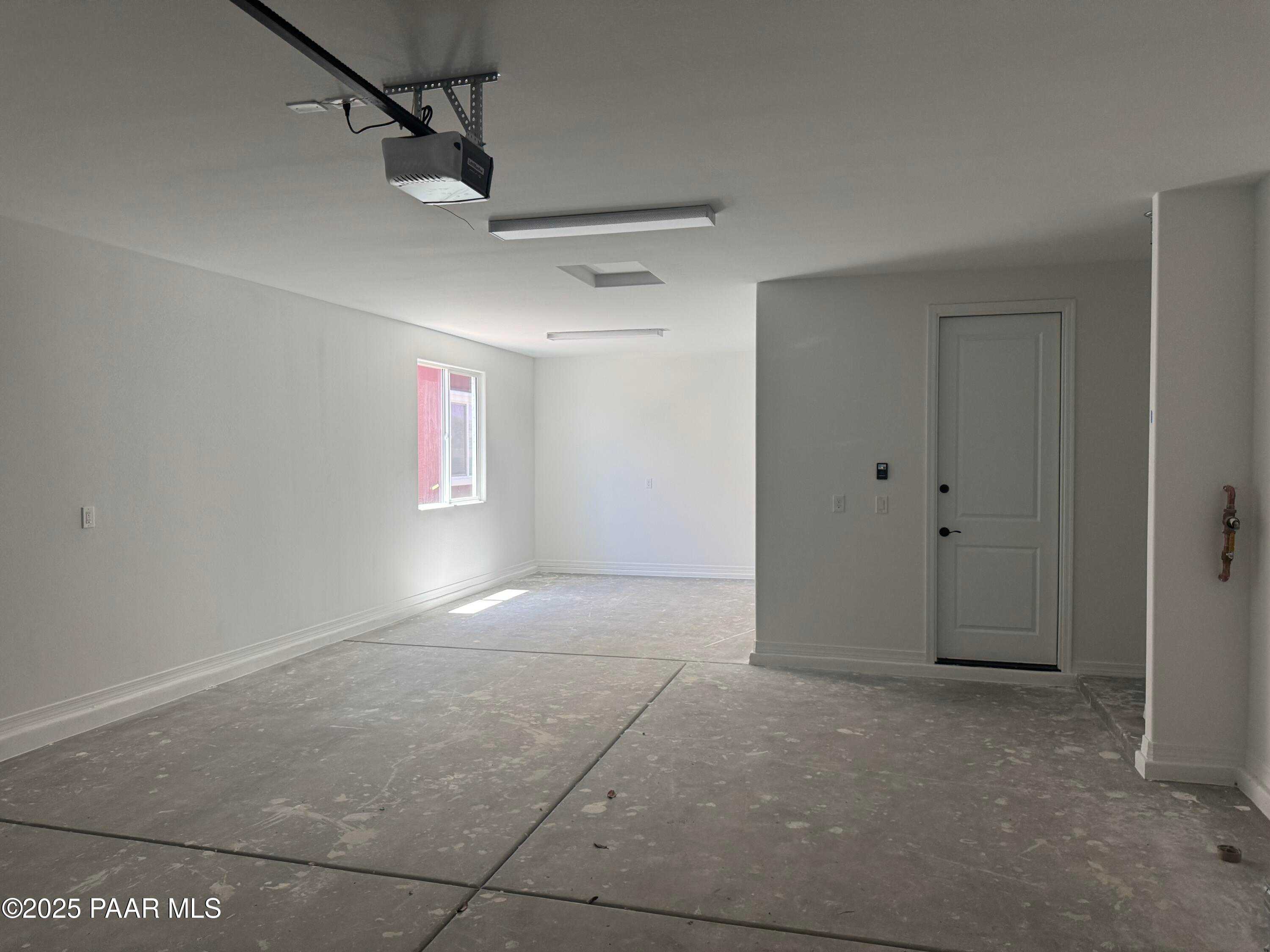 Spacious 3-car garage with high ceilings, overhead door, and white walls in Davidson Homes The Durango II A, Westwood, Prescott, Arizona