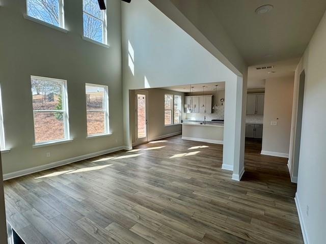 Spacious open living room with vaulted ceilings, hardwood floors, large windows, and adjacent kitchen in The Danbury C, Buford, Georgia