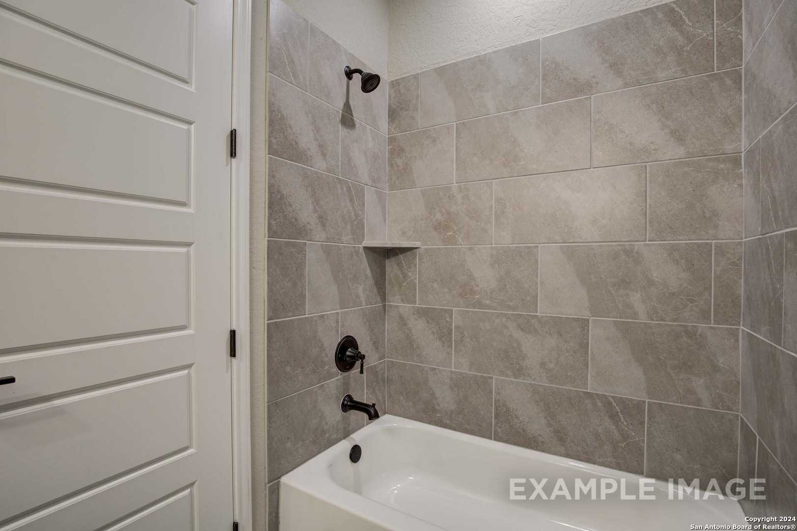 Modern master bathroom featuring gray subway tile shower, freestanding tub, and black fixtures in Davidson Homes The Rockford G, San Antonio