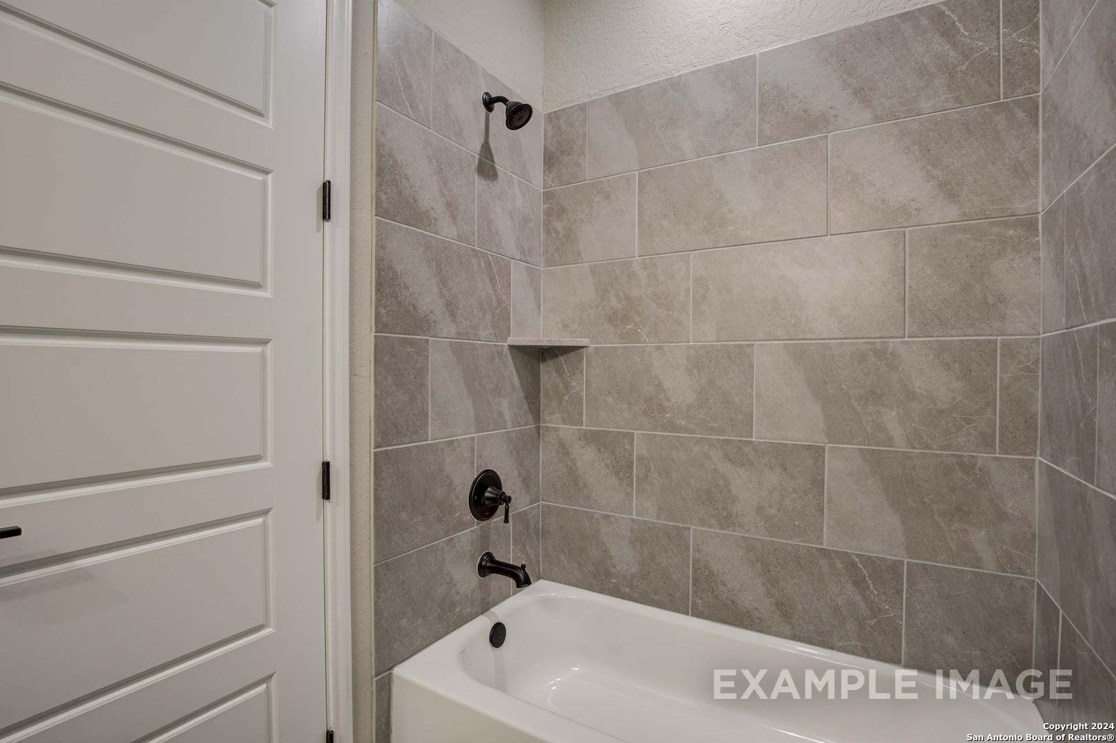 Modern master bathroom featuring gray subway tile shower, freestanding tub, and black fixtures in Davidson Homes The Rockford G, San Antonio