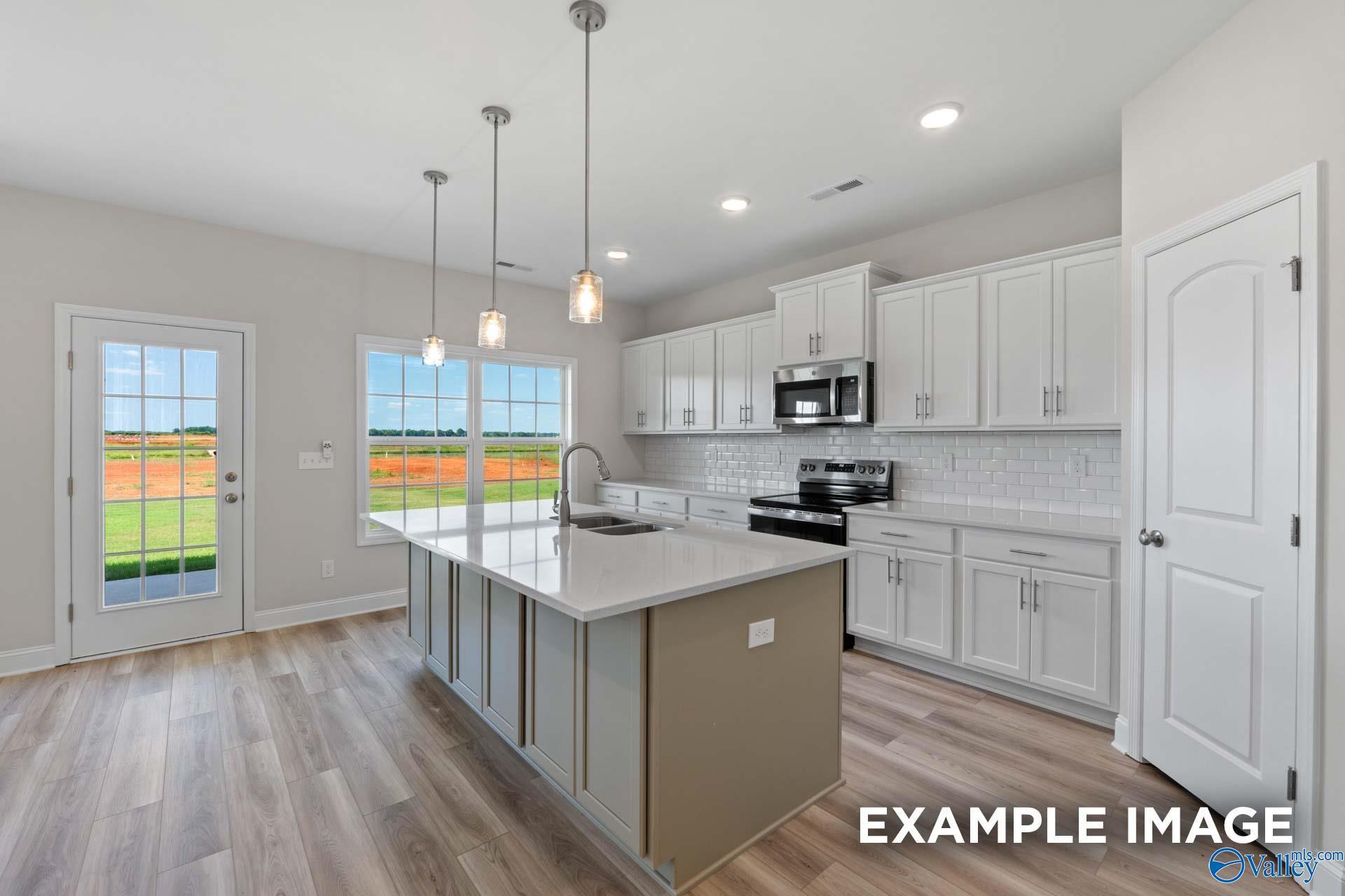 Modern kitchen featuring white shaker cabinets, quartz island, stainless steel appliances, subway tile backsplash in The Madison A, Toney, AL